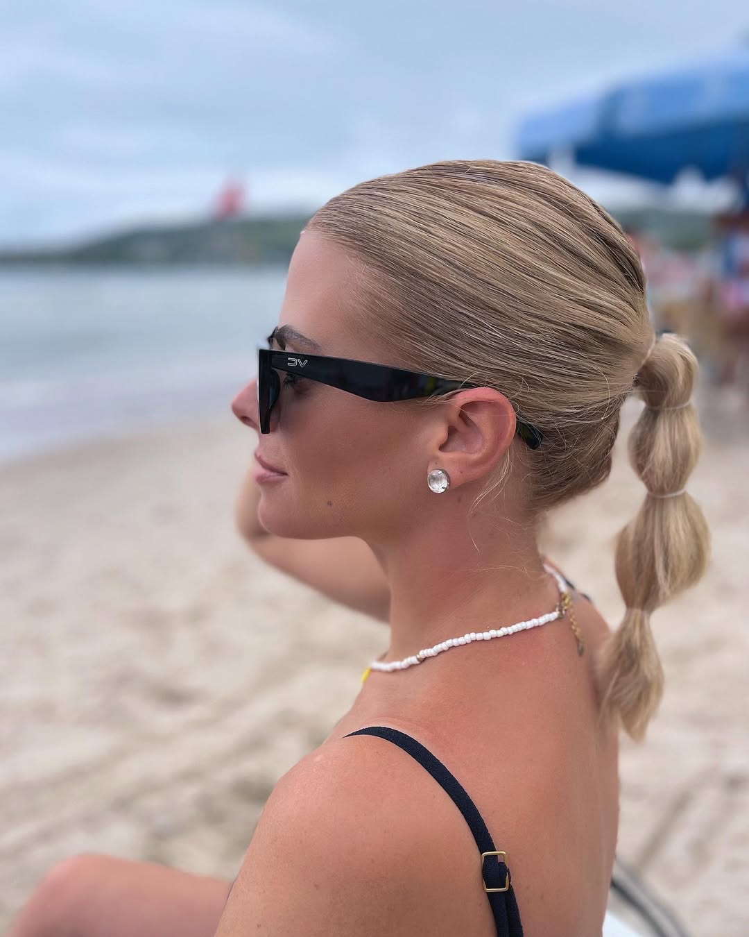 Blonde woman with sun-kissed, natural wavy summer beach hair, styled away from her face, soaking up the sun on a tropical vacation.