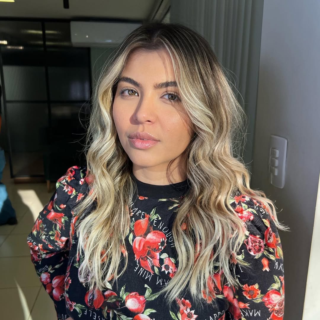 Woman with long, wavy blonde hair blowing in the summer beach breeze, showcasing natural summer beach hair ideas for 2026. A perfect relaxed style for seaside vacations.