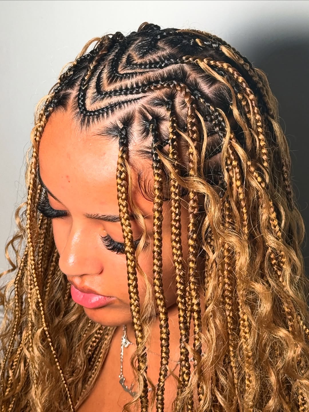 Close-up of a woman with long dark hair styled in intricate summer braids ideas 2026, featuring small, tightly woven cornrows on top leading into flowing box braids. Her hair is accented with small silver beads, perfect for hot weather or vacation.