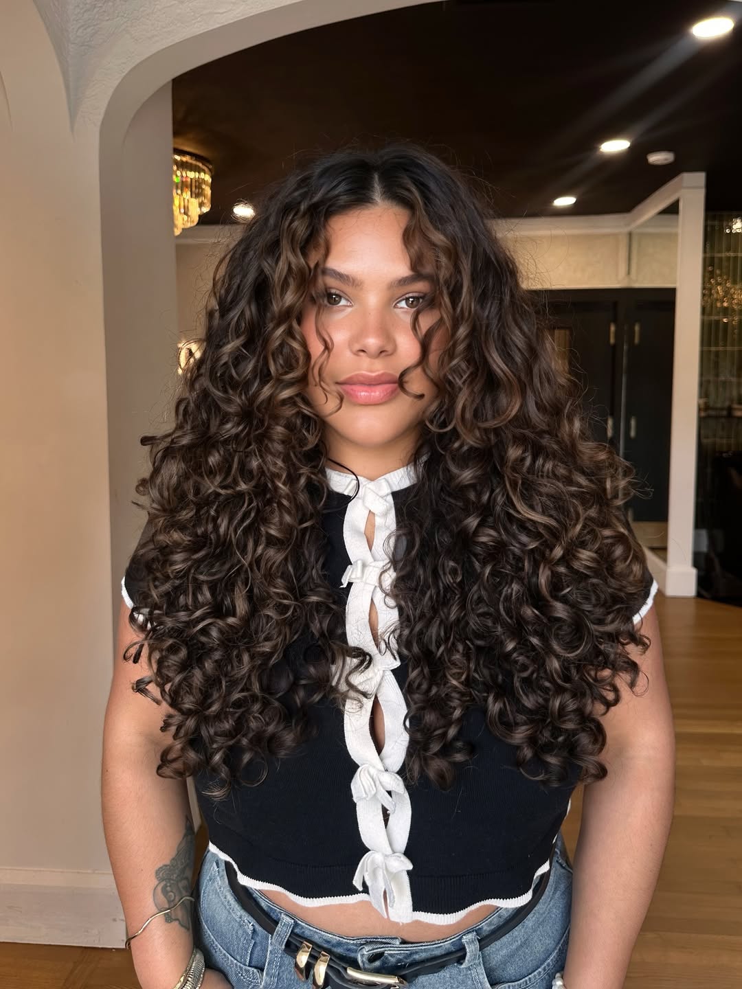 Close-up of a woman with beautiful, voluminous brown summer curly hairstyles 2026, showcasing defined ringlets and a natural, sun-kissed glow perfect for a casual day out.