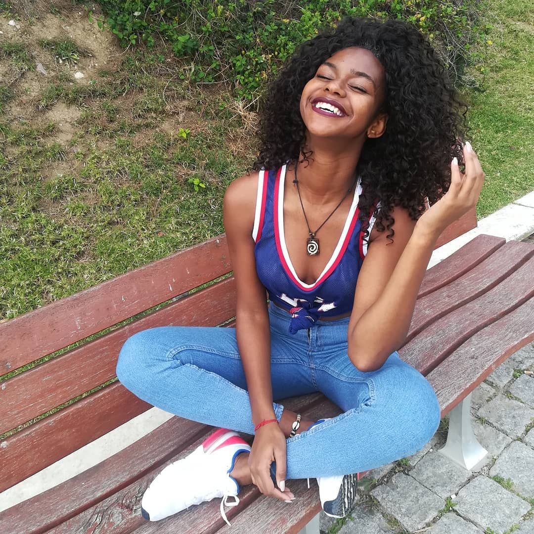 Beautiful Black woman smiling with a chic, intricate braided updo, perfect for summer hairstyles for black women. Her hair is artfully styled, highlighting her features for a sunny day.