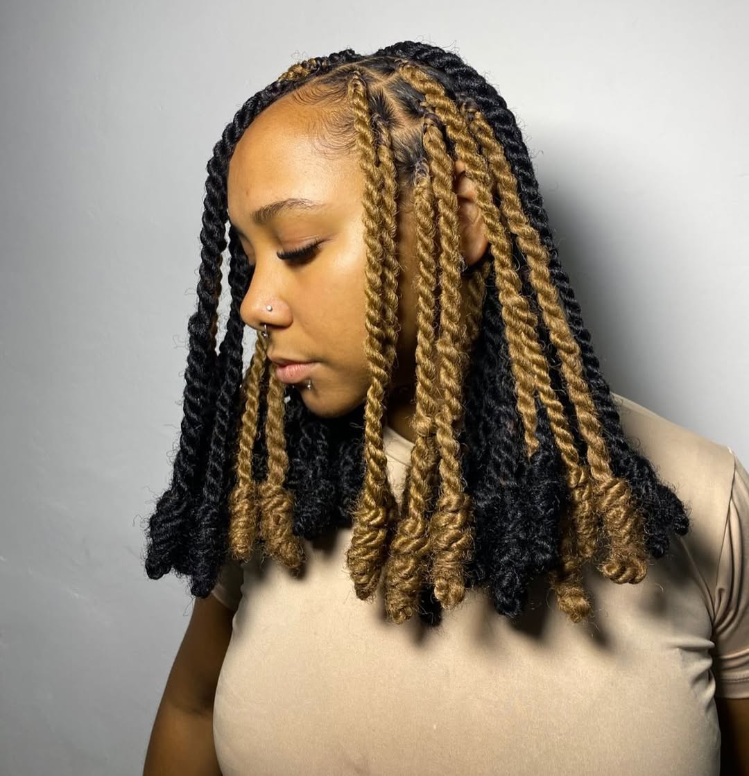 Close-up of a Black woman with vibrant fuchsia box braids stylishly swept to the side, showcasing a chic summer hairstyle perfect for 2026. Her braids are neatly parted, highlighting the intricate detail and trendy color choice for warm weather events.