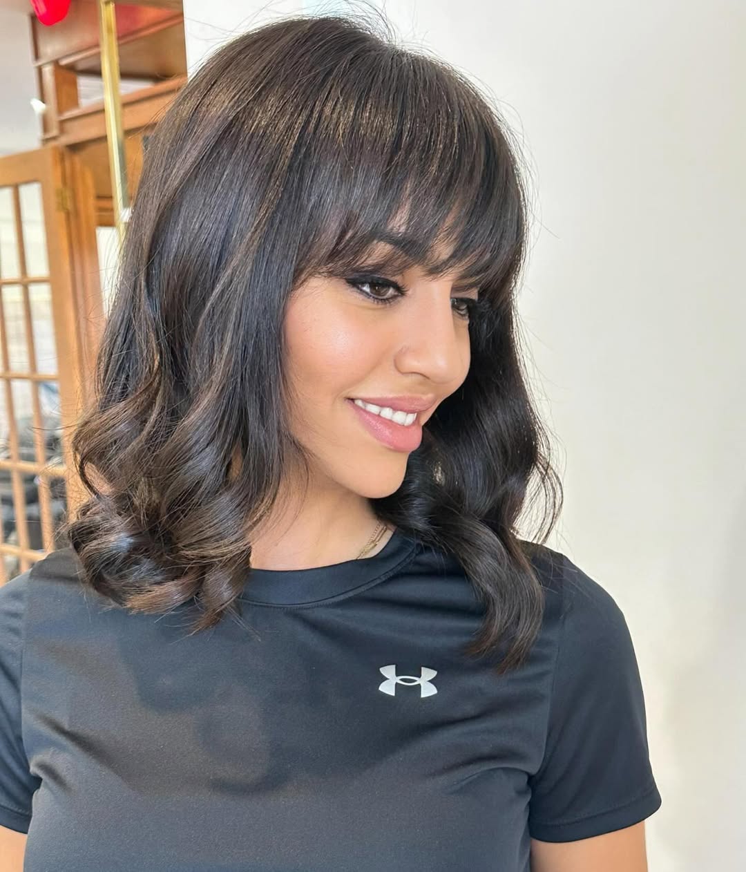 Close-up of a woman with a chic half-up top knot, ideal for summer hairstyles for medium hair 2026. Her brunette hair is casually styled, showing off face-framing layers perfect for a warm weather everyday look.