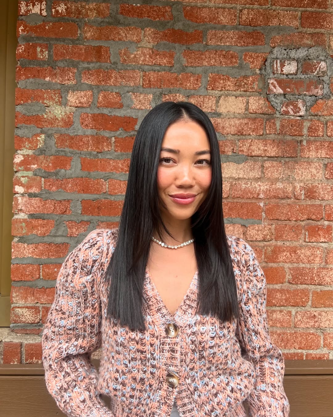 Woman showcasing a stylish, relaxed ponytail with face-framing strands, a perfect summer hairstyle for medium hair, complementing a vibrant floral dress.