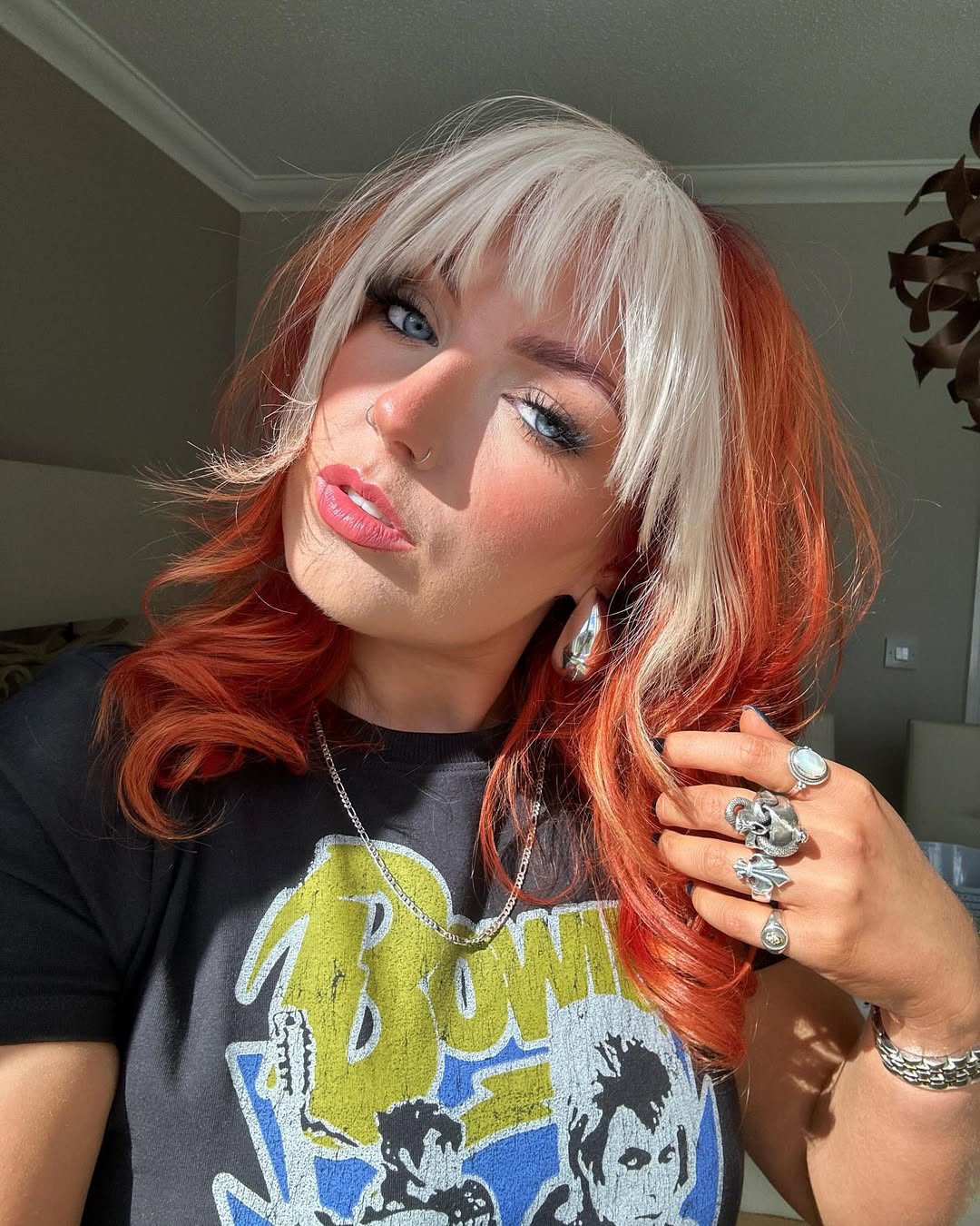 A woman with medium-length, wavy auburn hair, styled to highlight her true summer hair color 2026. She is wearing a relaxed neutral-toned linen top, suggesting a casual yet chic summer vibe.