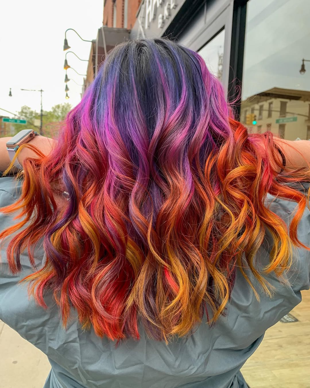 Woman with long, flowing auburn hair (true summer hair color 2026) styling it with a soft wave. This trendy hairstyle frames her face perfectly for a casual, effortless look.