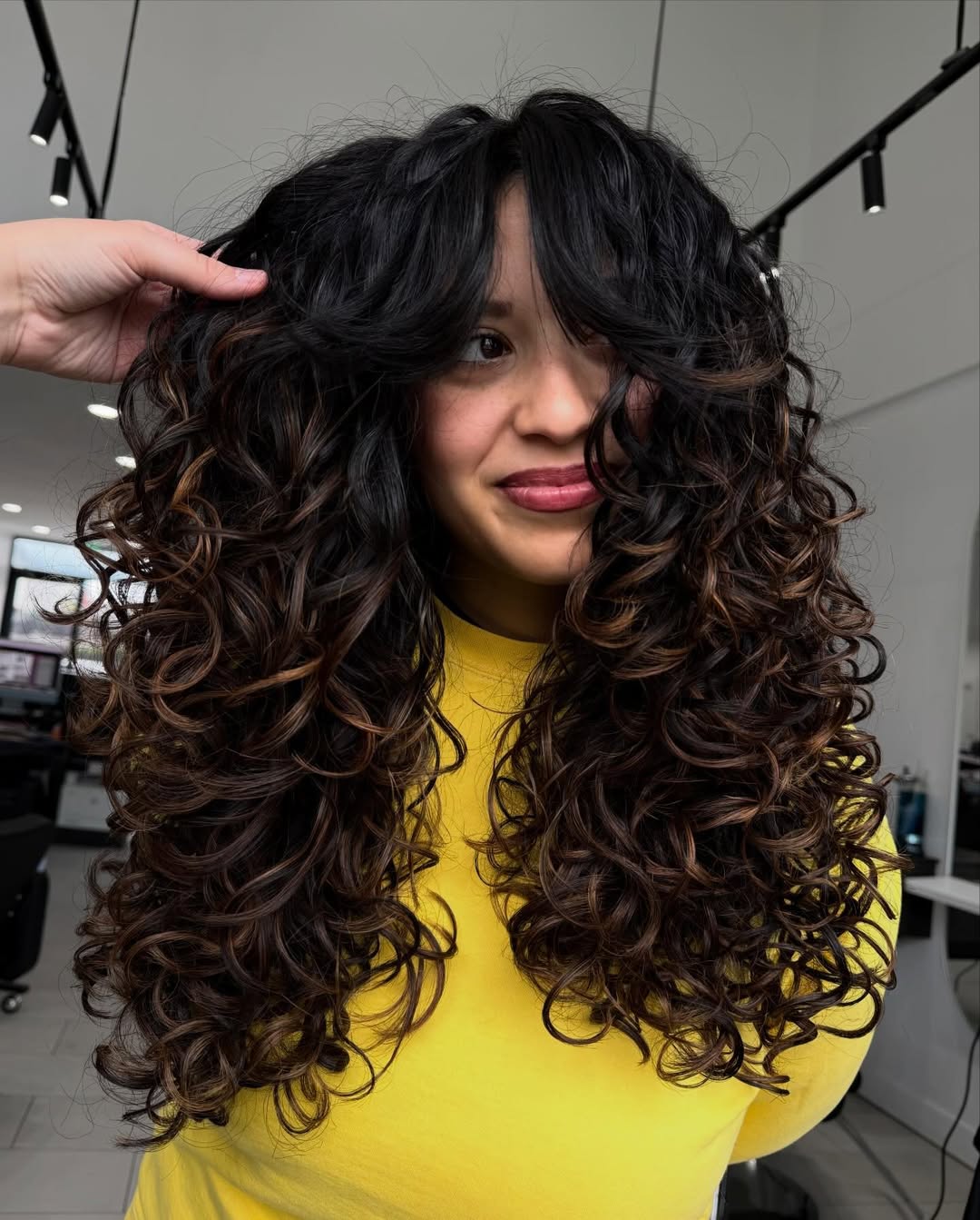Gorgeous Curly Layers with Subtle Caramel Highlights and Bangs