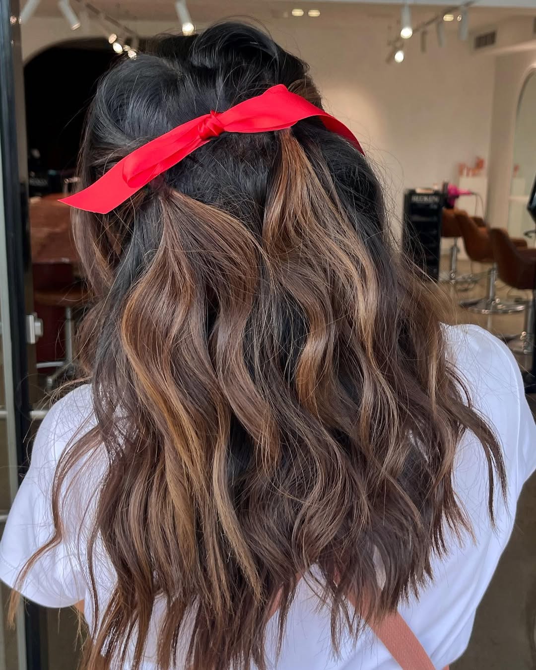 Wavy Chestnut Balayage Half-Up With Red Ribbon