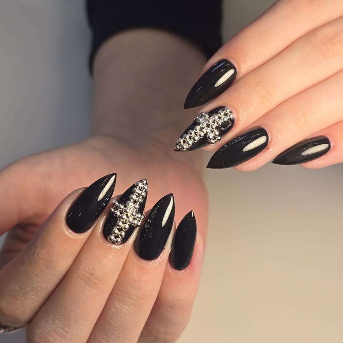 Glossy Black Stiletto Nails with Silver Cross Embellishments
