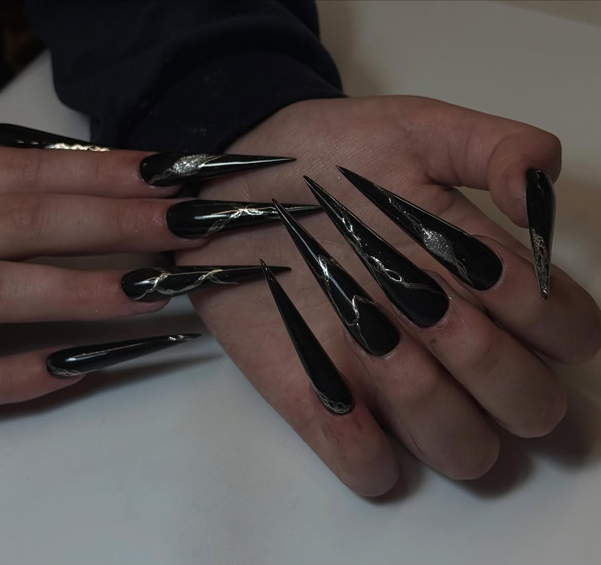 Glossy Black Stiletto Nails With Silver Swirl Art