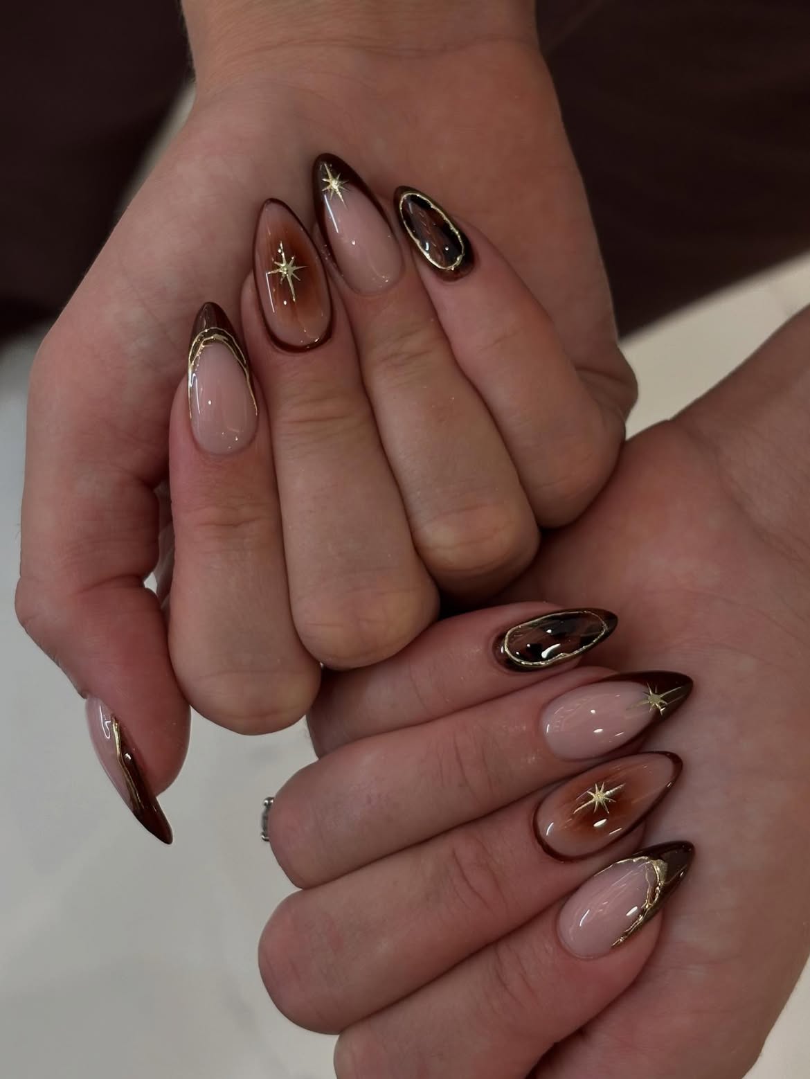 Glossy Chocolate Swirl Almond Nails with Gold Accents