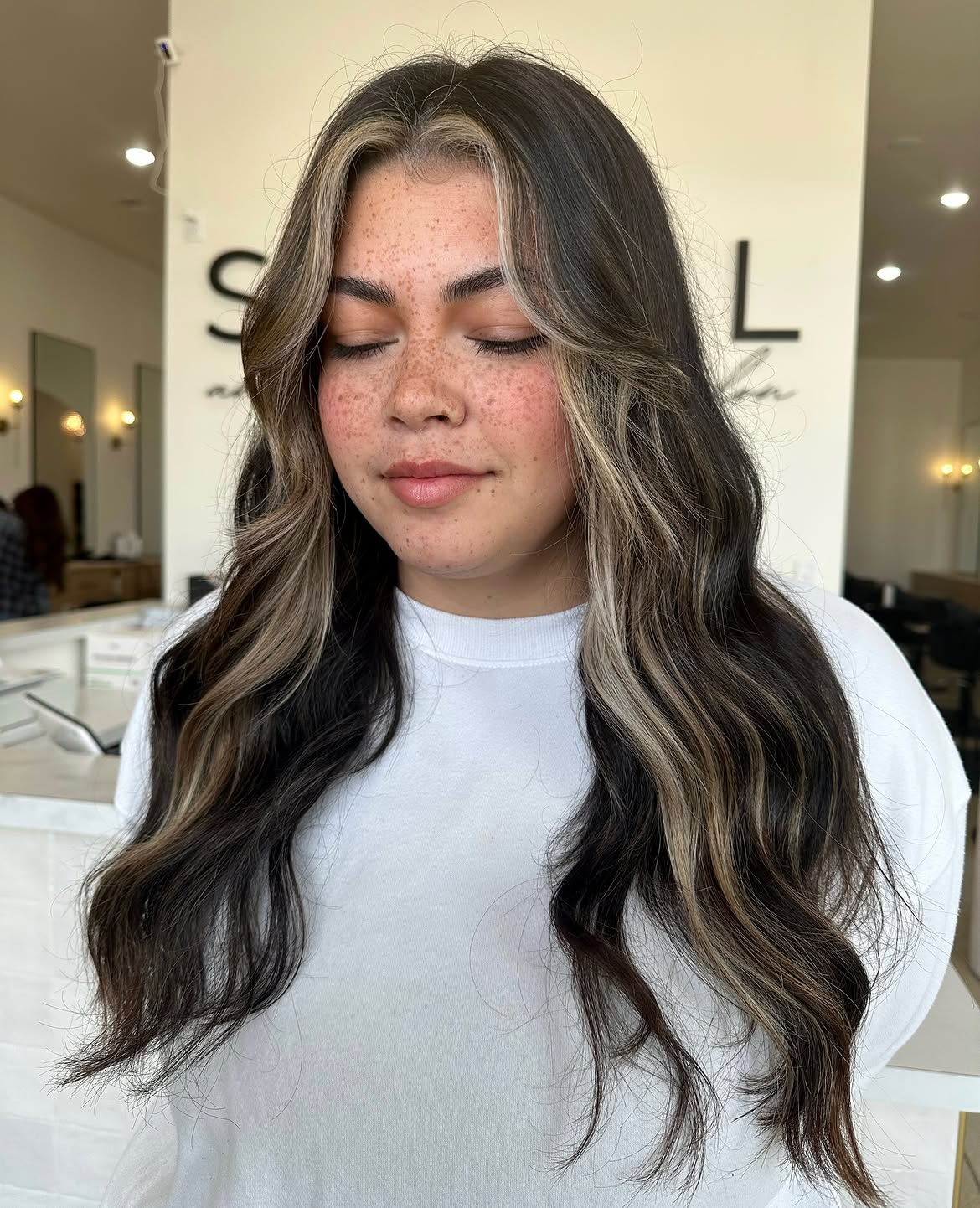 Bold Face-Framing Highlights On Dark Wavy Hair
