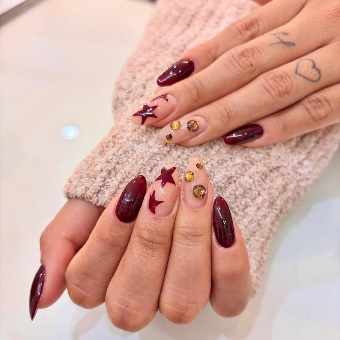 Deep Wine Stiletto Nails with Gold Star Accents