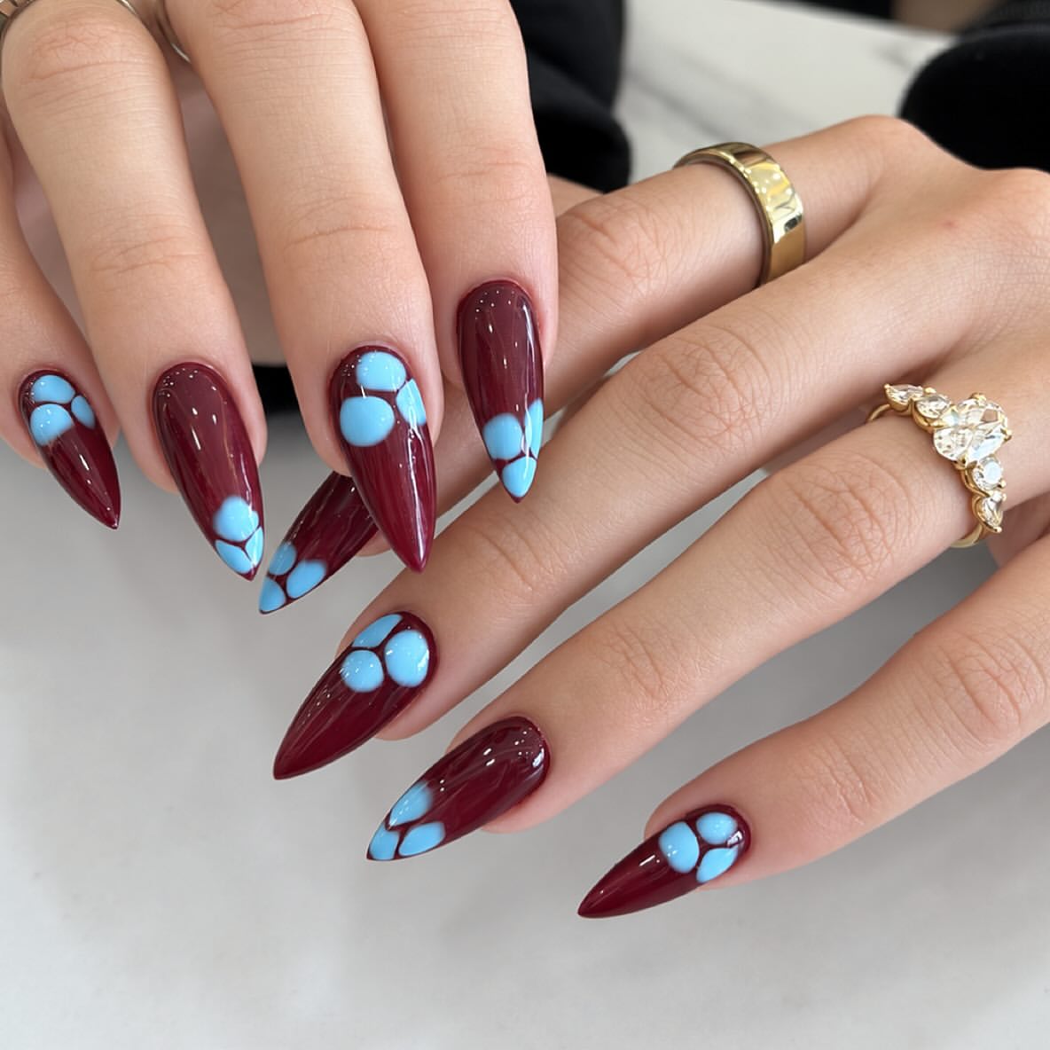 Glossy Burgundy Stiletto Nails with Light Blue Petal Art