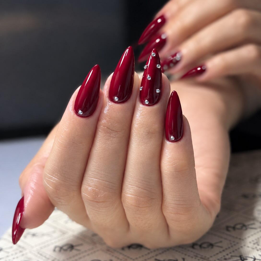 Glossy Burgundy Stiletto Nails with Silver Rhinestones