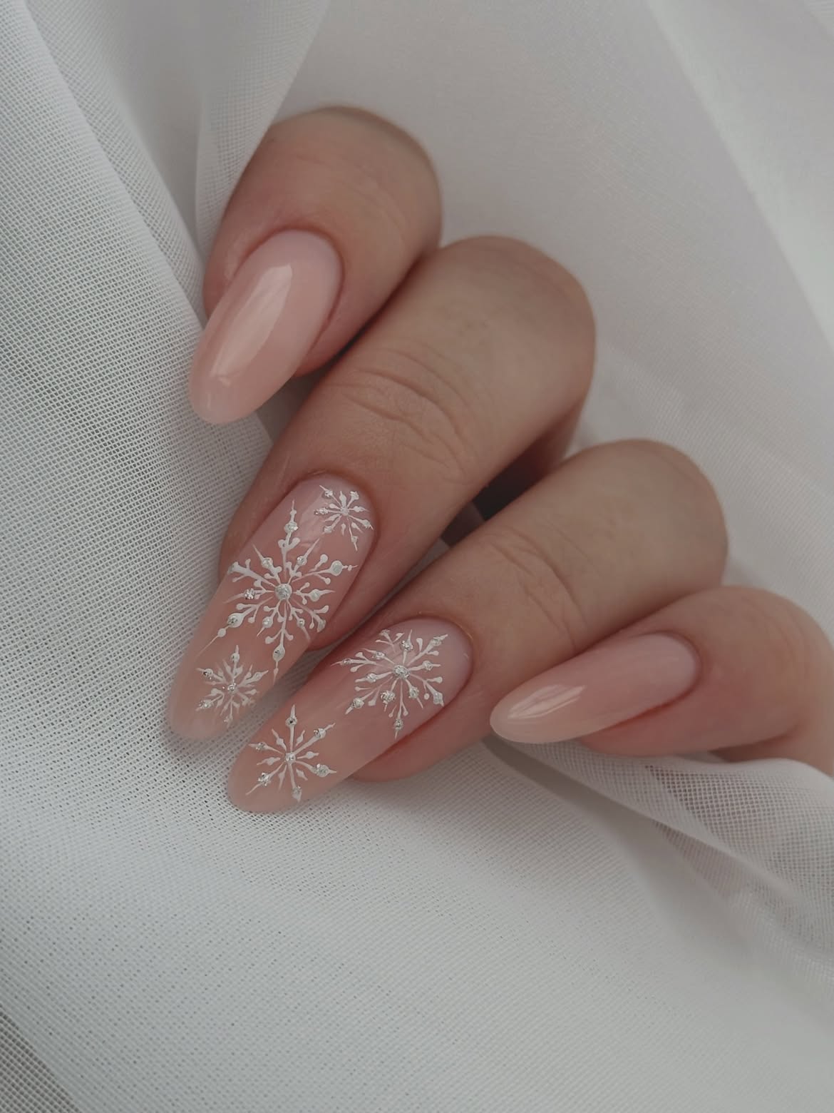 Glossy Nude Almond Nails With White Snowflakes