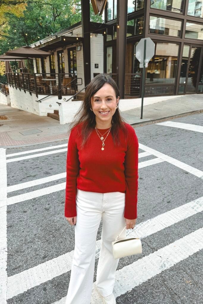 Vibrant Red Crewneck Sweater With White Wide Leg Jeans, Close-Up Take Vibrant Red Crewneck Sweater With White Wide Leg Jeans, Close-Up Take — Red Sweater Outfit